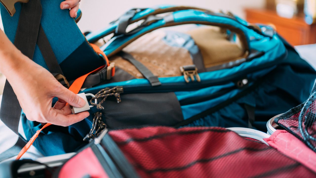 Person putting a travel lock on their luggage.