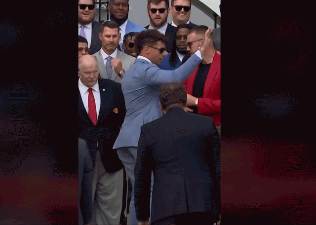Kansas City Chiefs QB Patrick Mahomes escorts teammate Travis Kelce away from the microphone during a White House event.